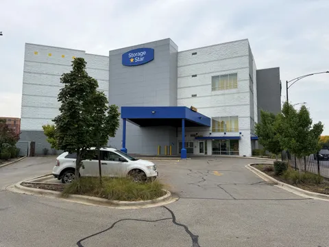 A white car parked in front of a multi-story Storage Star facility in Chicago on N McCormick Blvd with a blue loading bay awning