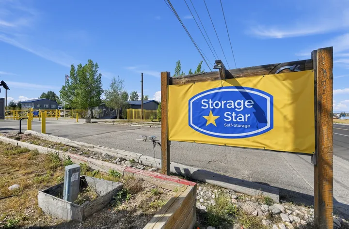 A yellow and blue Storage Star banner sign stands beside the paved entrance to the Laramie self-storage facility on Skyline Rd