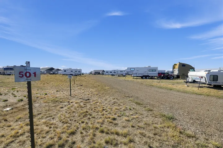 Outdoor vehicle storage in Laramie on Skyline Rd, with gravel paths and various recreational vehicles parked under a clear blue sky