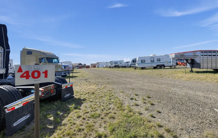 Outdoor gravel parking lot for RV and boat storage in Laramie on Skyline Rd, featuring semi-trucks and travel trailers under a blue sky