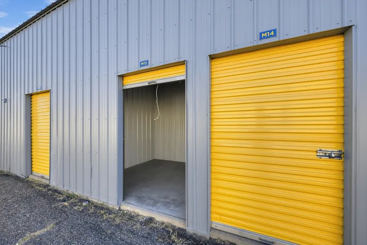 An open, empty small drive-up storage unit in Laramie on Skyline Rd with a yellow roll-up door beside a closed, larger drive-up unit