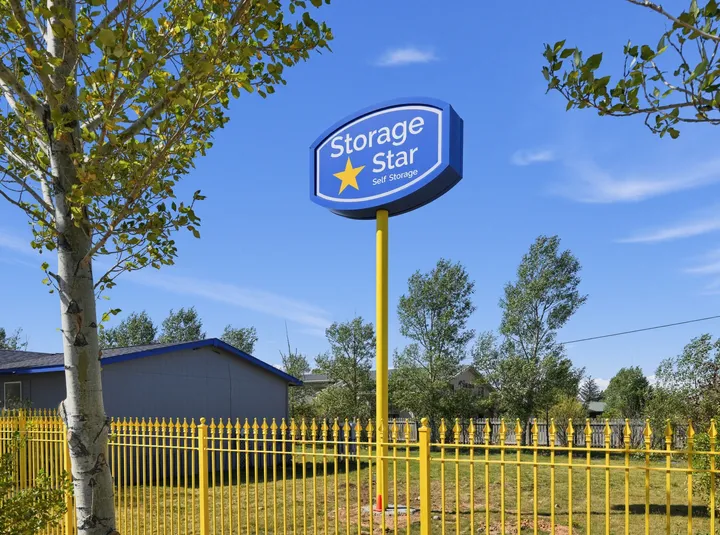 Pylon sign at Storage Star Self-Storage in Laramie, WY, on a tall yellow pole behind a yellow metal fence