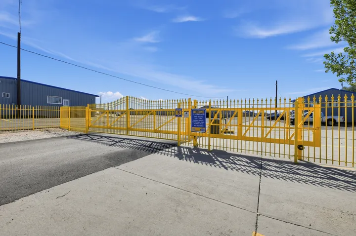 A yellow metal security gate with facility signage stands at the entrance of Storage Star Self-Storage in Laramie on Skyline Rd