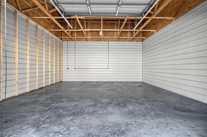 The interior of an empty 10x30 storage unit in Laramie, WY, with corrugated metal walls, concrete flooring, and exposed wooden rafters