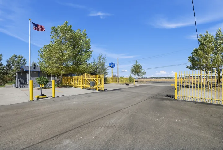 Entrance to Storage Star Self-Storage in Laramie on Skyline Rd with an open yellow metal gate, a keypad, and a Storage Star pylon sign under a blue sky