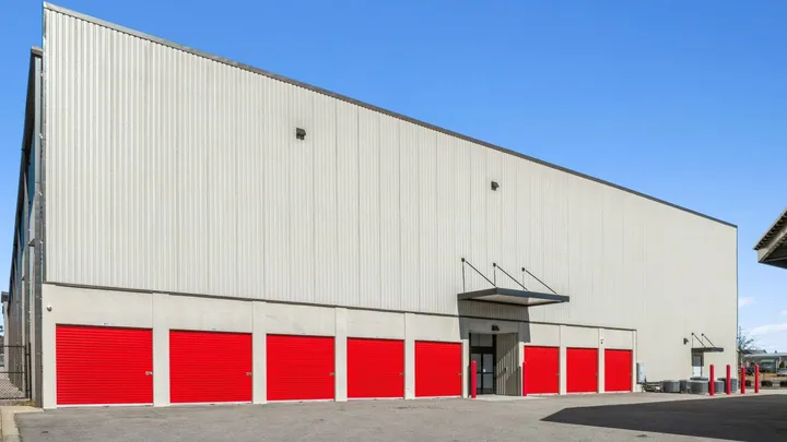 Large multi-story storage building with tan corrugated siding and a row of red drive-up storage units in Aiken on Hamilton Dr