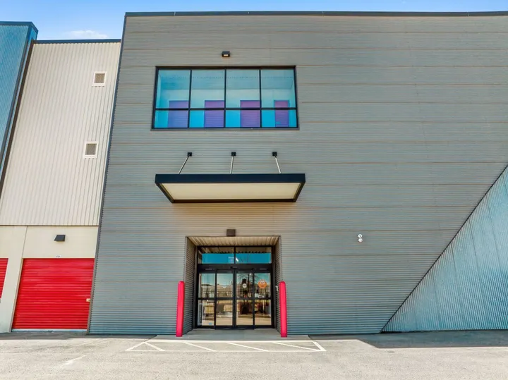 Exterior of a gray corrugated metal storage facility with glass entrance doors and red drive-up storage units in Aiken on Hamilton Dr