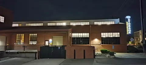 Exterior of a brick storage building at night with lit windows and a Storage Star sign