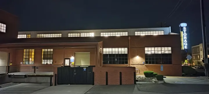 Exterior of a brick storage building at night with lit windows and a Storage Star sign