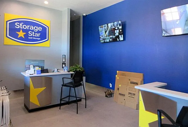 Storage Star rental office featuring a blue wall, reception desks, security monitors, and cardboard packing boxes