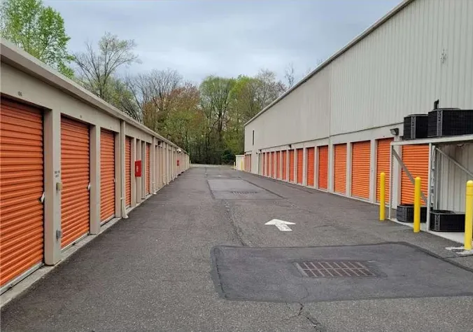 Outdoor drive-up self storage units in Bordentown, NJ, with orange roll-up doors along an asphalt driveway between two buildings