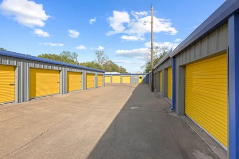 Rows of gray outdoor drive-up storage units in Irving on N O'Connor Rd with yellow roll-up doors and a paved driveway