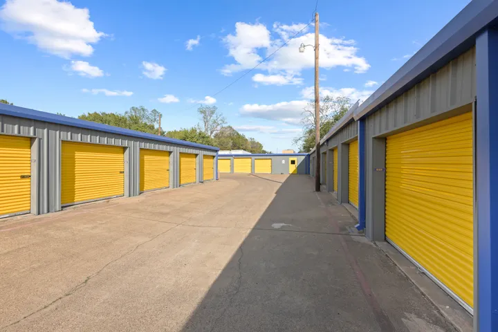 Rows of gray outdoor drive-up storage units in Irving on N O'Connor Rd with yellow roll-up doors and a paved driveway
