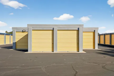 Yellow roll-up drive-up storage units in Vacaville, CA, along a paved driveway against a blue sky