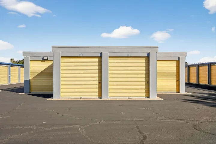 Yellow roll-up drive-up storage units in Vacaville, CA, along a paved driveway against a blue sky