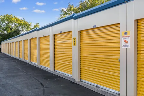 Outdoor drive-up storage units in Vacaville, CA, with yellow roll-up doors and a five-mile-per-hour speed limit sign