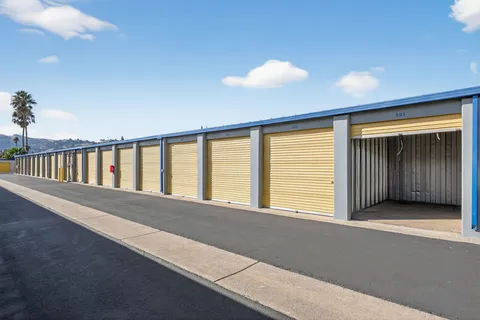 Outdoor drive-up storage units in Vacaville on Bella Vista Rd with yellow roll-up doors along a paved driveway under a blue sky