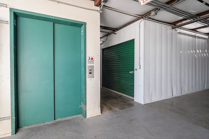 Green elevator doors and a hallway leading to  green roll-up indoor storage units in Vacaville on Bella Vista Rd