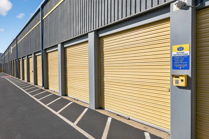 Yellow drive-up storage units in Vacaville on an exterior building wall next to an asphalt driveway