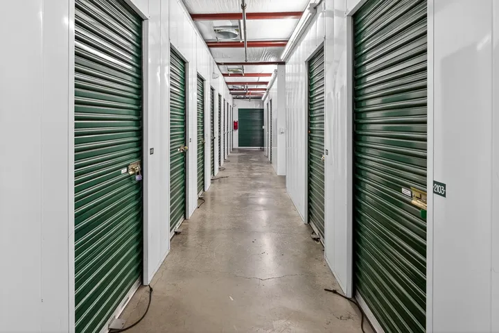 Indoor hallway with white walls, concrete floors, and rows of green climate-controlled storage units in Vacaville, CA, on Bella Vista Rd