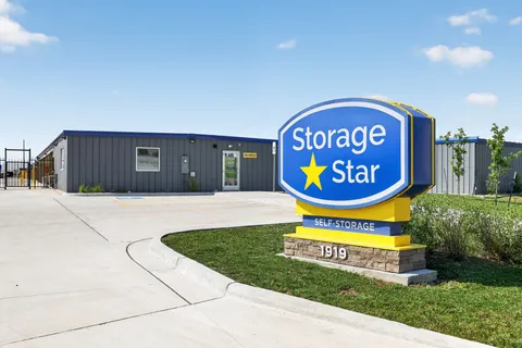 A monument sign for Storage Star self-storage in Cheyenne, WY, stands in front of a gray-sided office building and sidewalk