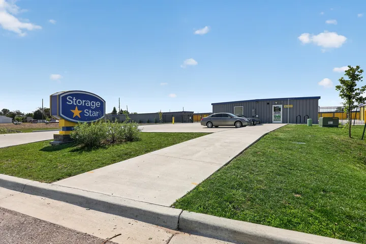 A sign for Storage Star Self-Storage in Cheyenne at 1919 Wyott Drive, featuring a sidewalk leading to a gray leasing office and parking area