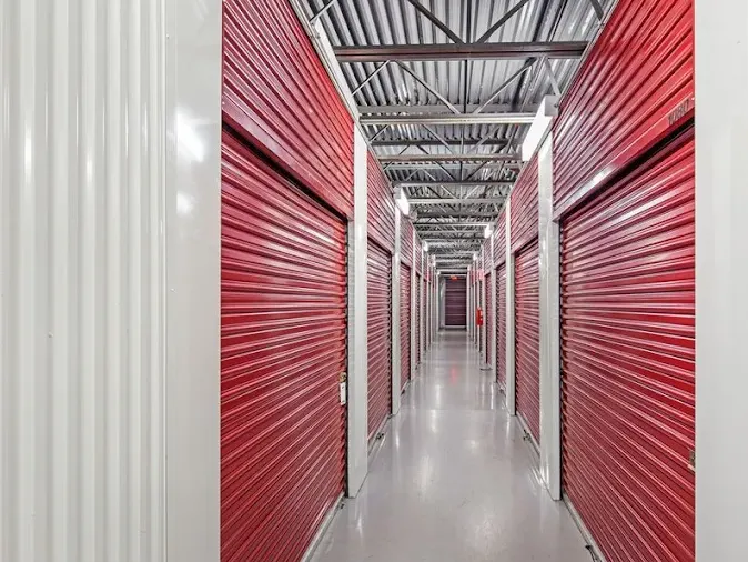 Indoor hallway of Storage Star Cinnaminson, featuring red roll-up unit doors and white metal siding