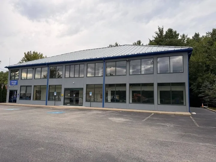 Two-story office building of Storage Star Self-Storage in Coventry, RI, at 1185 Tiogue Ave, with glass windows and a metal roof beside a parking lot