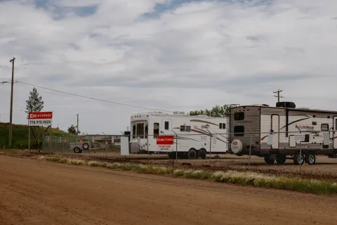 Outdoor RV and boat storage lot with campers parked behind a chain-link fence and red signage