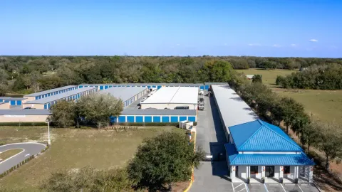 Aerial view of a self-storage facility with many rows of blue drive-up units and an office