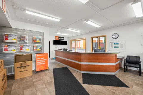 Self-storage office interior featuring a wood-panel reception desk, moving supplies, and Mini Mall Storage signage