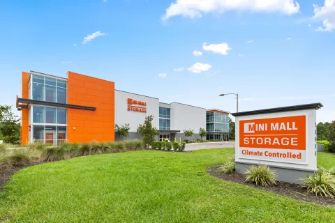 Exterior of a Mini Mall Storage facility with a large orange sign and modern multi-story building