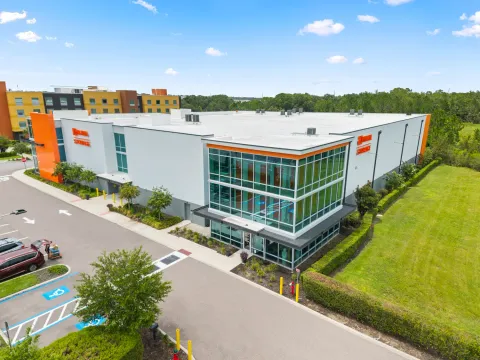 High-angle view of a multistory self-storage facility featuring a glass office entrance and paved parking lot
