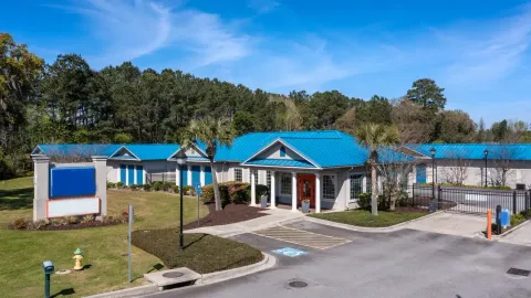 Exterior view of a self-storage rental office with blue metal roofing and palm trees under blue sky