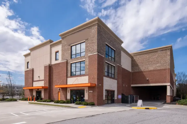 Exterior view of a multi-story brick storage facility office with orange awnings and a paved parking lot