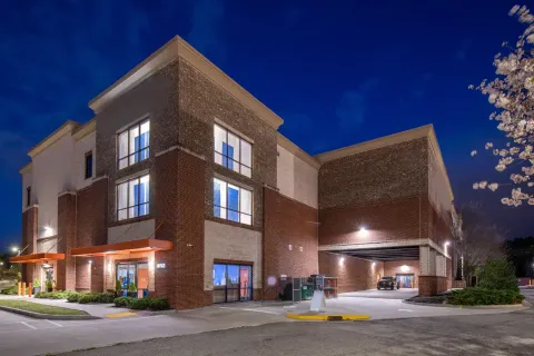 A multi-story brick storage facility at night featuring an office entrance and a covered loading bay