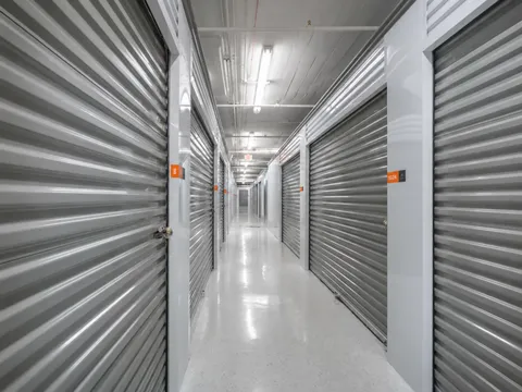 Exterior view of a modern, multi-story self-storage facility with numerous rollup doors on the ground level.