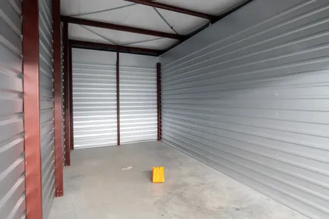 An empty drive-up self-storage unit featuring corrugated metal walls, a concrete floor, and high ceilings