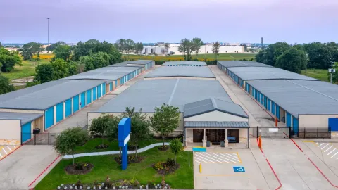 An aerial view of a self-storage facility featuring rows of blue units and an office building