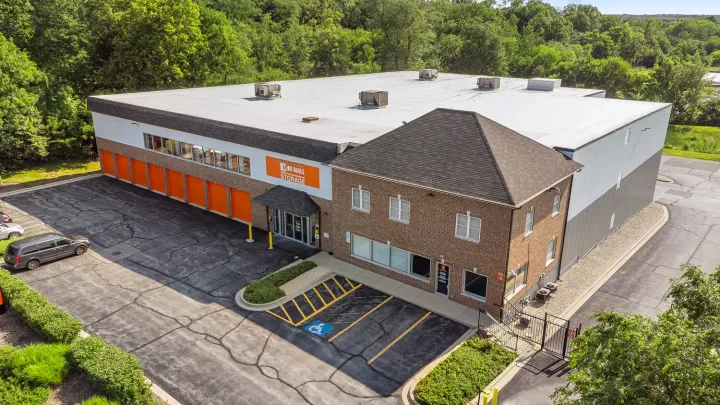 Aerial view of a brick and metal Mini Mall Storage building with orange bay doors and parking