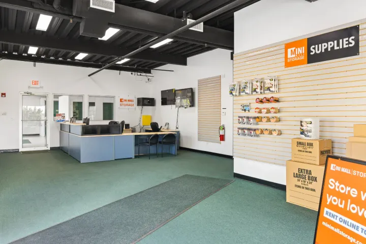 Storage facility office featuring a blue service desk and a wall displaying packing supplies and boxes