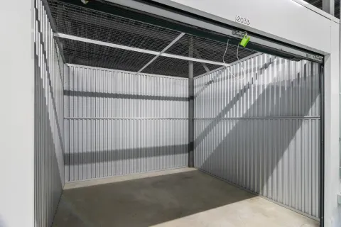 Interior view of an empty storage unit with corrugated metal walls and a wire mesh ceiling