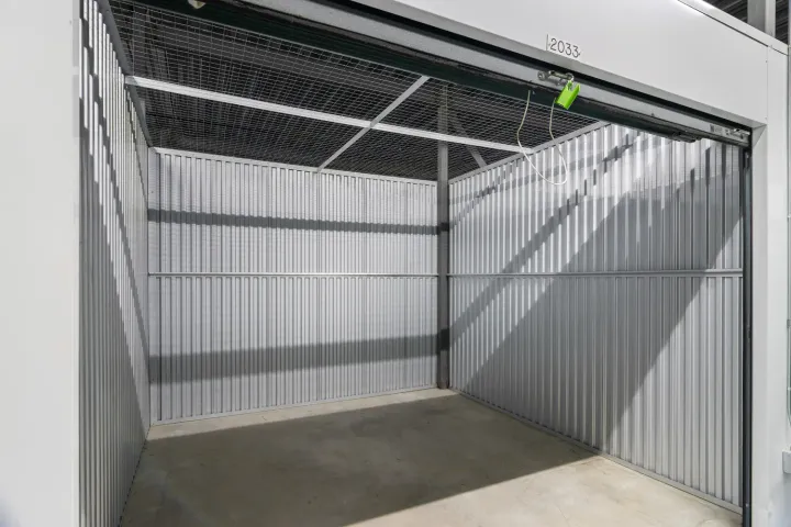Interior view of an empty storage unit with corrugated metal walls and a wire mesh ceiling
