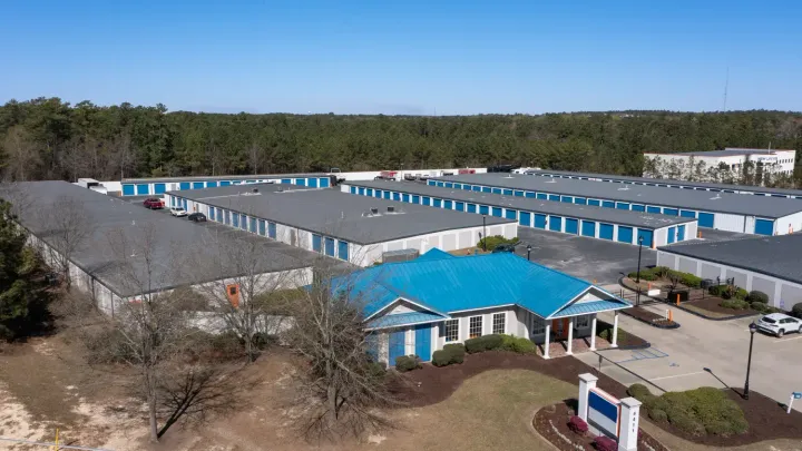 Aerial view of a storage facility featuring a blue-roofed office building and several long rows of units