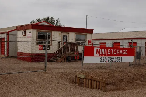 A Mini Mall Storage sign on a chain link fence in front of a facility office