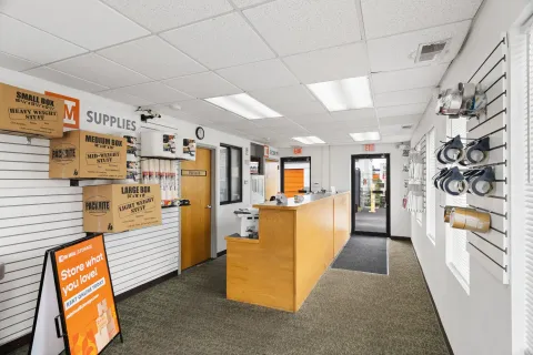 A storage facility rental office featuring a wooden counter, retail moving supplies, and glass exit doors