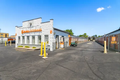 White Mini Mall Storage office building next to a gated entrance and rows of drive-up units