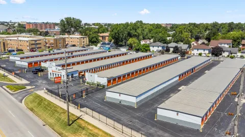 Aerial view of a self-storage facility with several long buildings and orange roll-up doors
