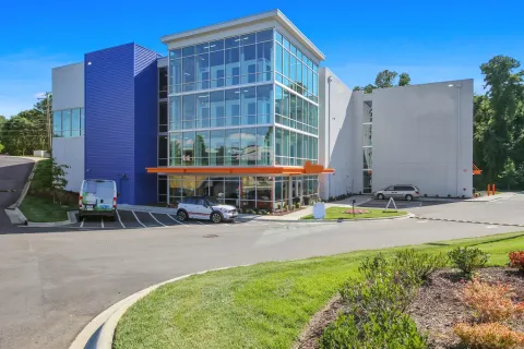 Exterior of a multi-story storage building with a glass facade, orange awning, and parking area
