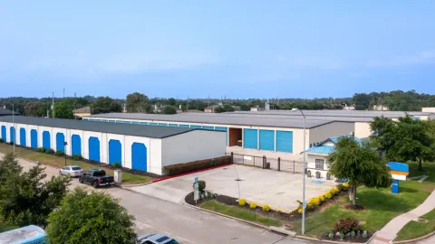 Aerial view of a self-storage facility with gated access, blue roll-up doors, and parked vehicles